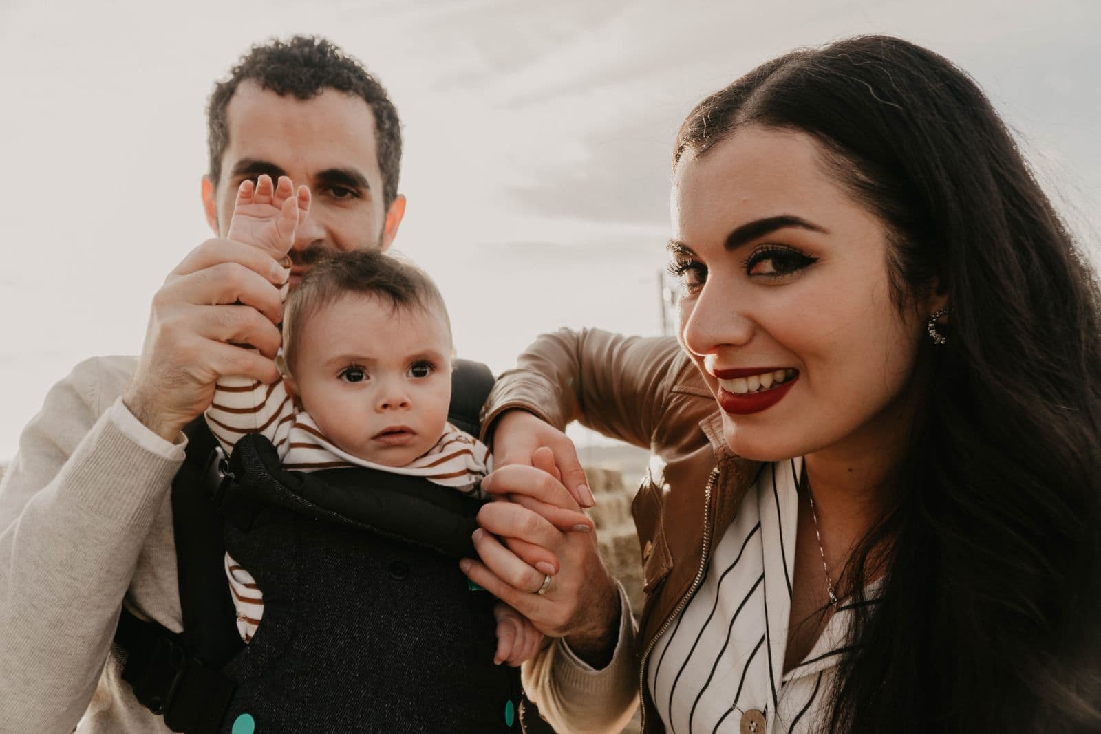 Two parents outdoors with a baby in a structured carrier