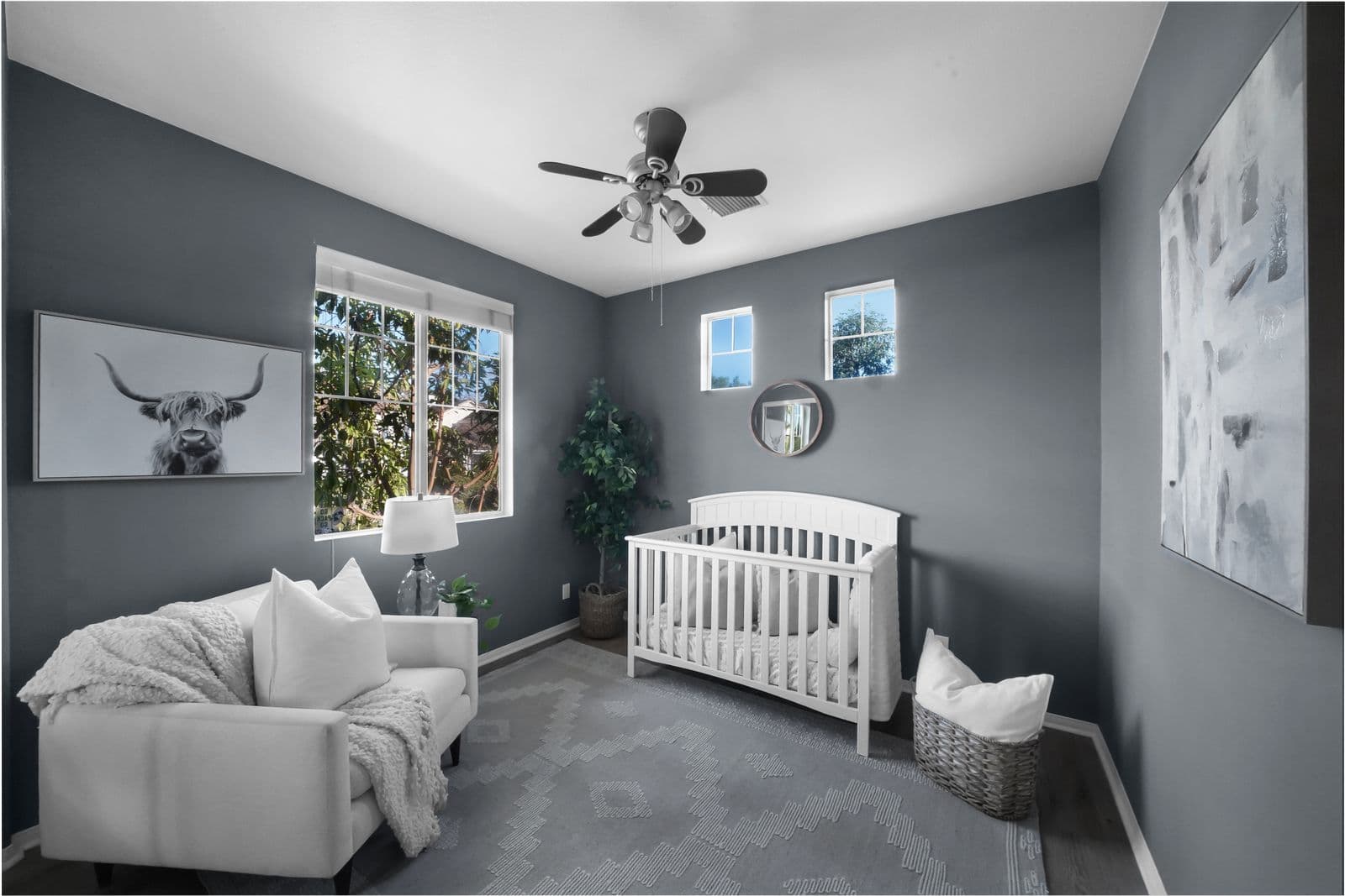 An empty white crib in a calm gray nursery with a chair and window nearby