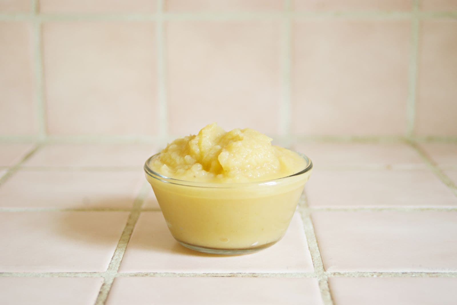 A small glass bowl of homemade fruit puree on a tiled kitchen counter